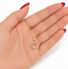 Gold necklace with a heart-shaped pendant held in a hand with red nail polish.