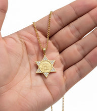 Gold Star of David pendant on a chain held in a hand against a white background