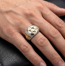 Close-up of a hand wearing a silver ring with gold accents on a dark background