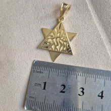 Gold star-shaped pendant next to a ruler on a textured surface