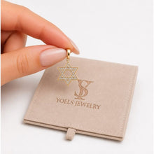 Gold star-shaped earring held above a Yoels Jewelry box on a white background