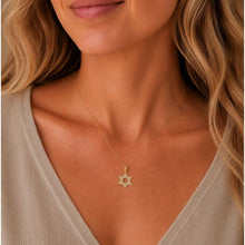 Gold necklace with a star pendant worn by a person