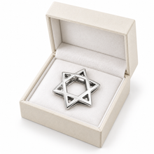 Gold Magen David pendant leaning against a gift box
