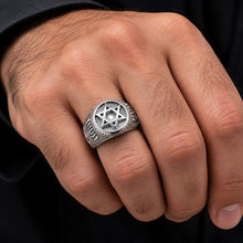 Silver  star of David ring with menorah design on a person's finger against a black 