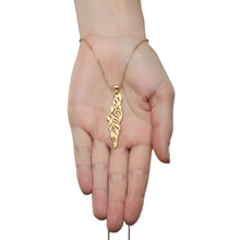 Gold necklace with a leaf-shaped pendant on a hand against a white background