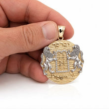 Ten Commandments gold pendant with lions and Hebrew blessing held by a hand against a white background. 