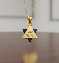 Gold and black triangular pendant necklace on a wooden surface with a blurred background