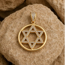 Gold Star of David pendant with diamonds on a stone surface